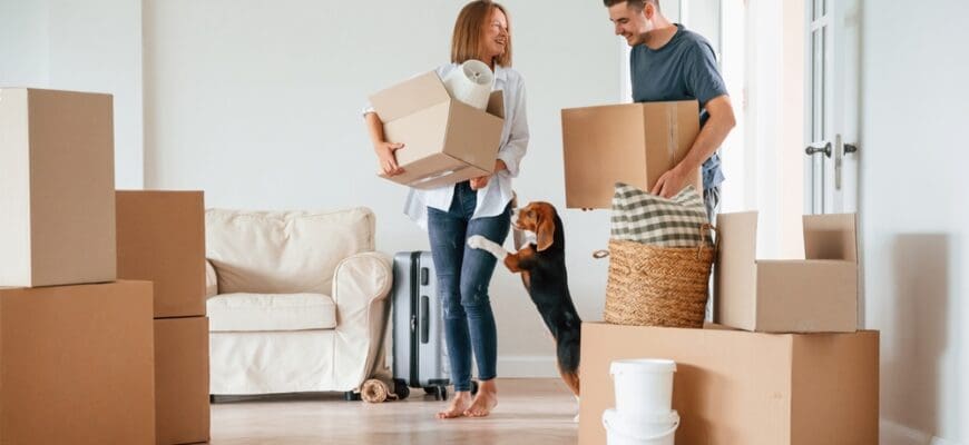 Two,Boxes,In,Hands.,Young,Couple,With,Dog,Are,Moving